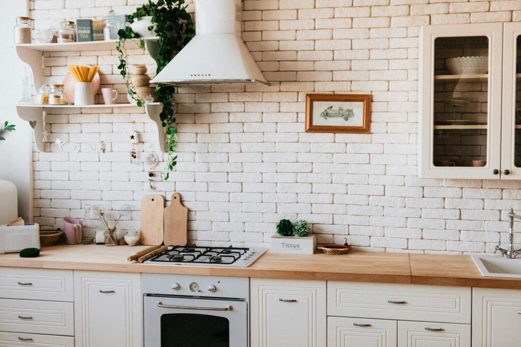 Kitchen with cream tiles and cupboards and wooden countertops with silver cooker