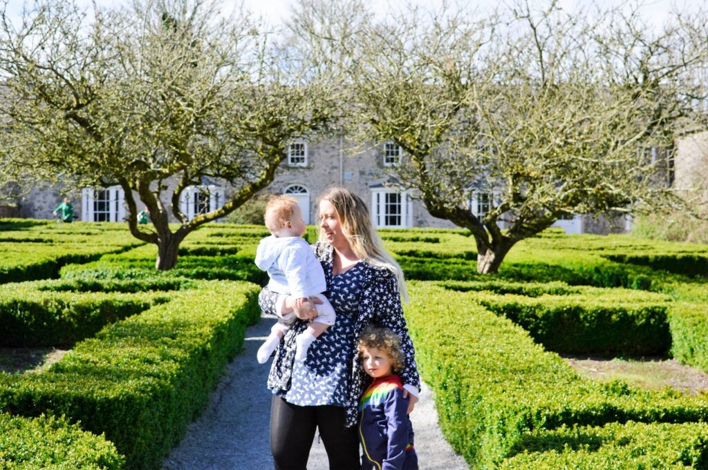 Mother and sons standing in a garden by two trees
