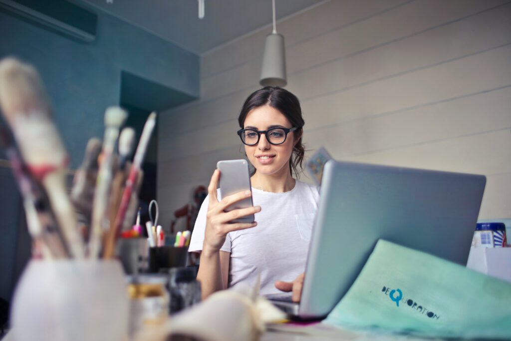 Woman with glasses sitting at a desk looking at a phone