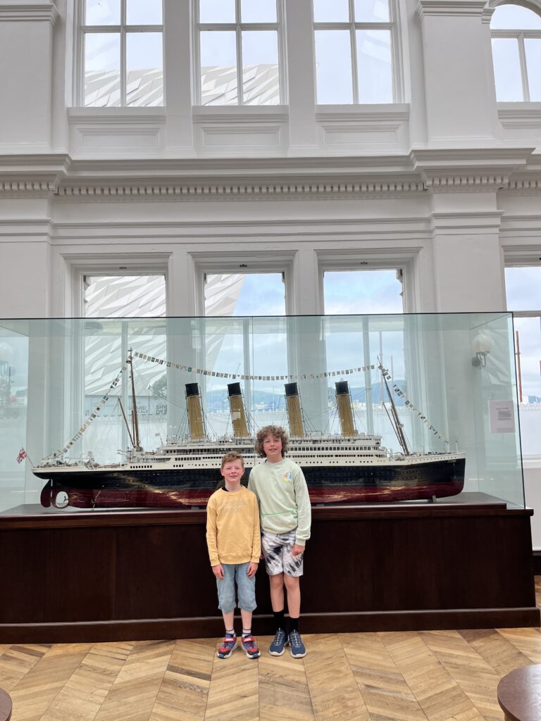 Two boys standing in front of a model of the Titanic