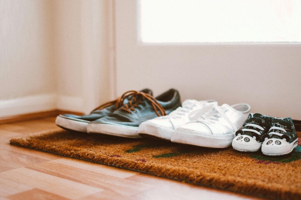 Men's, ladies and children's shoes lined up on a mat by a door