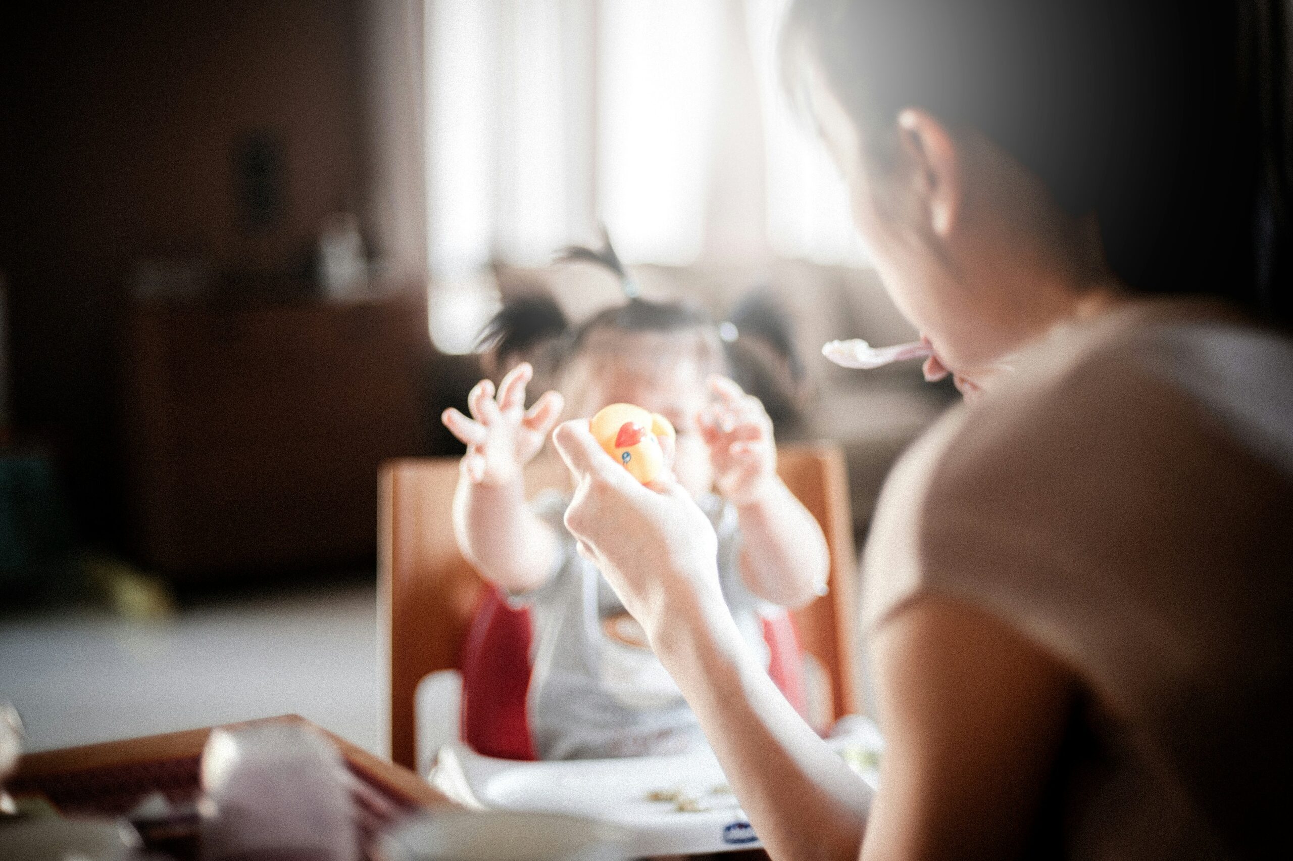 Woman feeding a baby, with a rubber duck in her hand