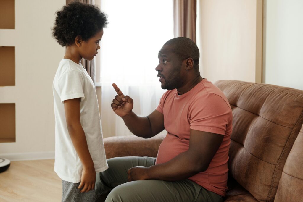 Man speaking with his son while sitting on a brown sofa