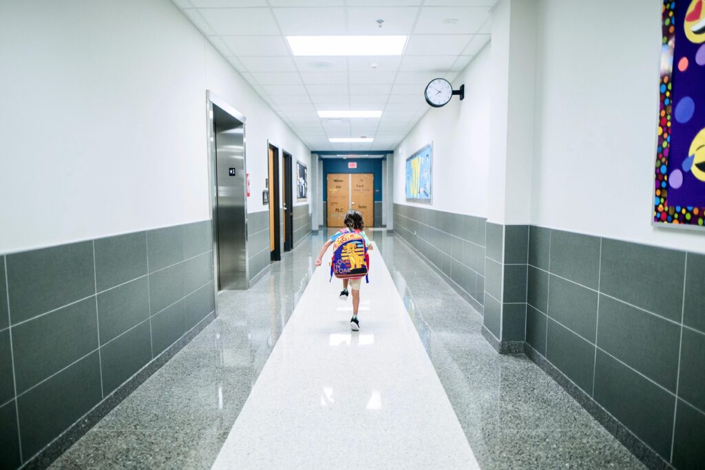Child skipping through a school corridor with a backpack on their back