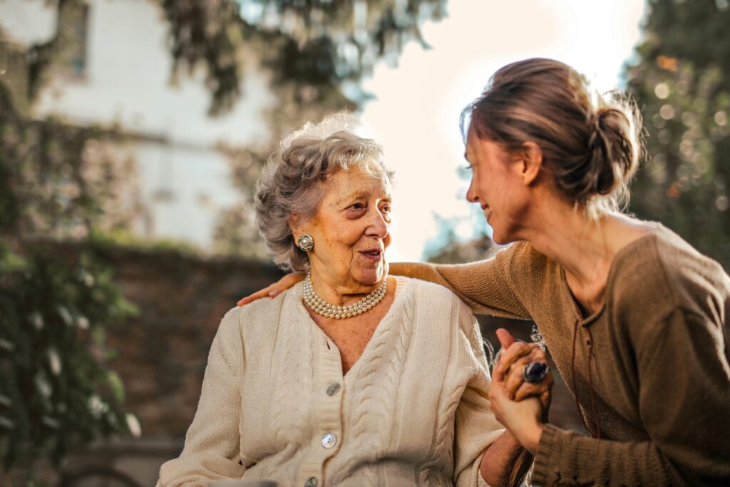 Elderly woman holding hands with a younger woman