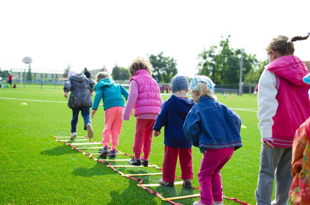 Children playing a jumping game on a green