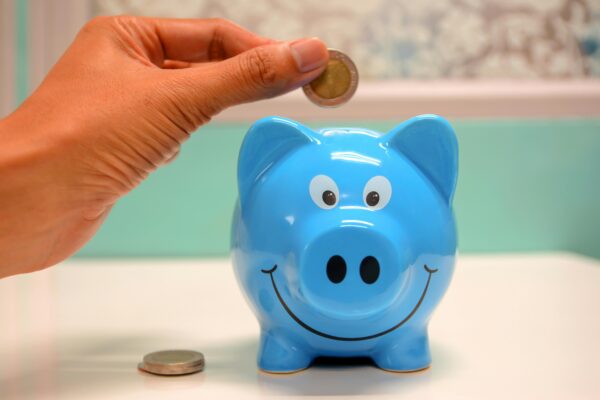 Someone putting a coin into a blue piggy bank