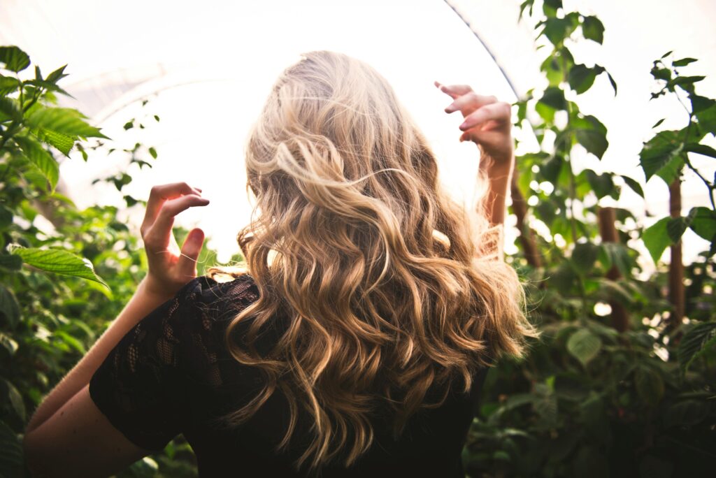 Blonde haired woman standing in the sunlight swishing her hair