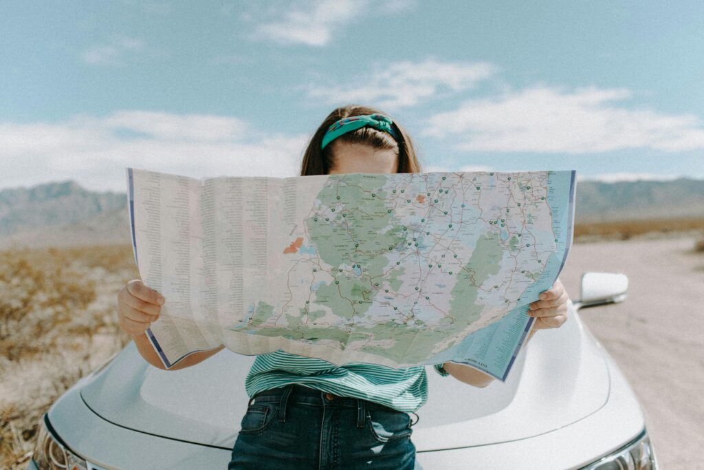 Woman looking at a map while sitting on a car bonnet