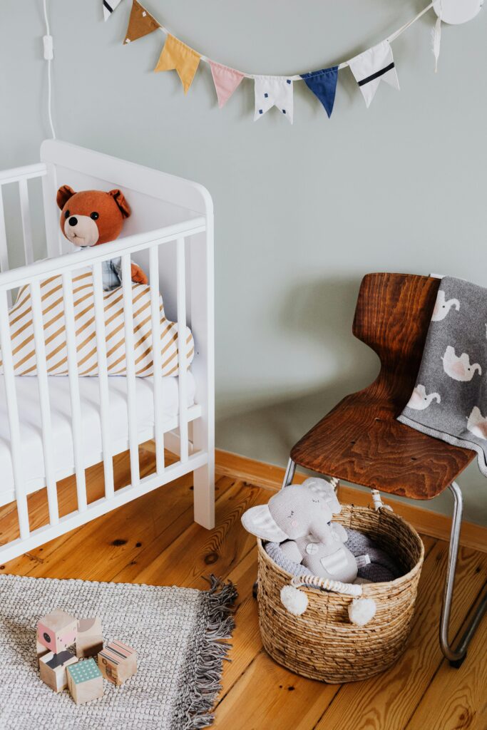 White baby cot beside a wooden chair