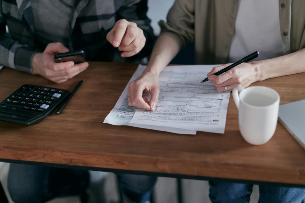 Couple managing finances with a calculator, forms and coffee cup on a desk