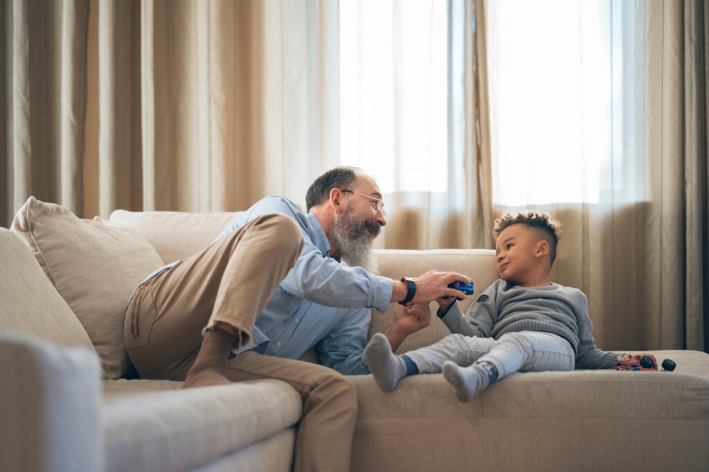 Grandfather and child sitting on a couch playing