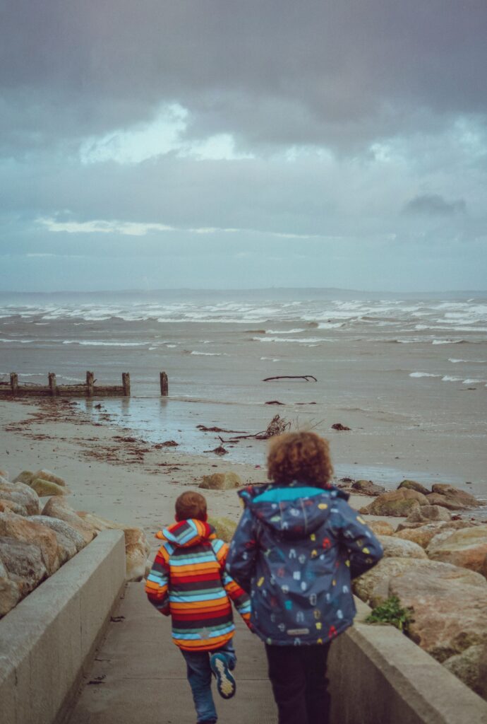 Two boys running towards the beach in Newcastle, Down