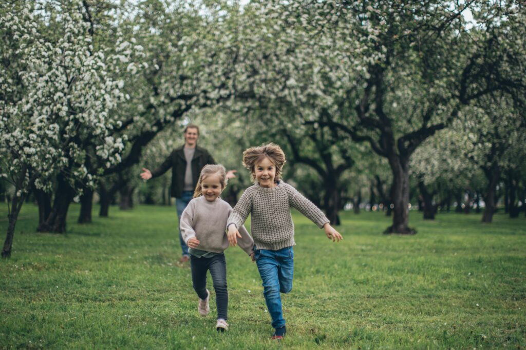 Father and children running in a park