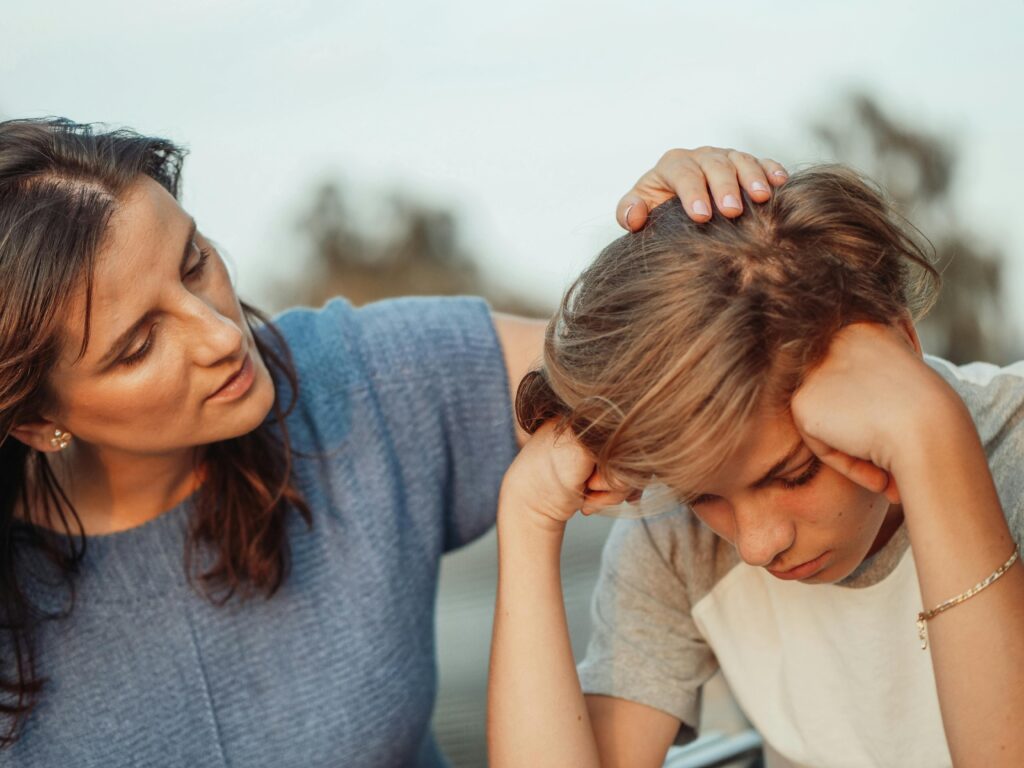 Mother in a blue shirt talking to a teenage boy in a white shirt