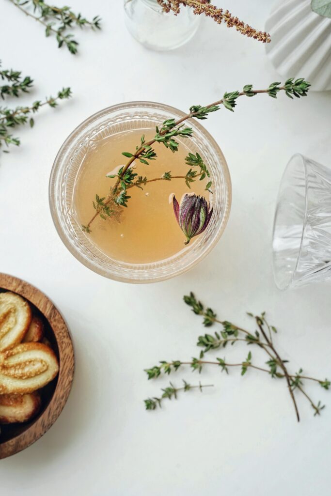 Cocktail glass on a table with herbs and flower