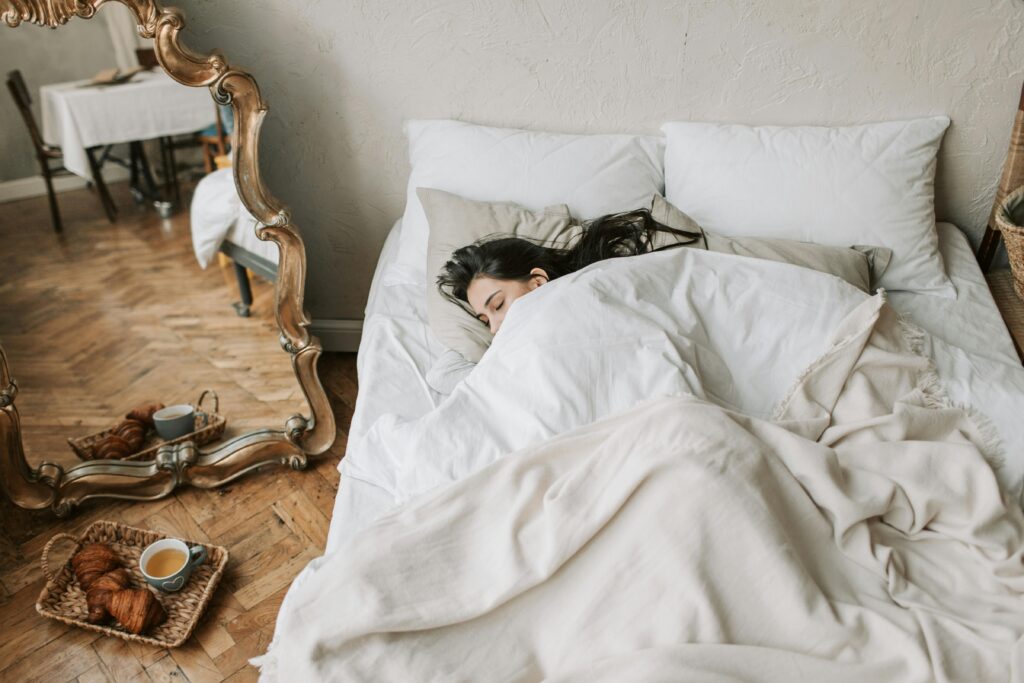 A woman asleep in bed with breakfast on the floor next to the bed