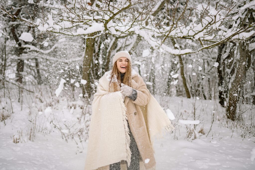 Woman standing in the snow with a blanket wrapped around her