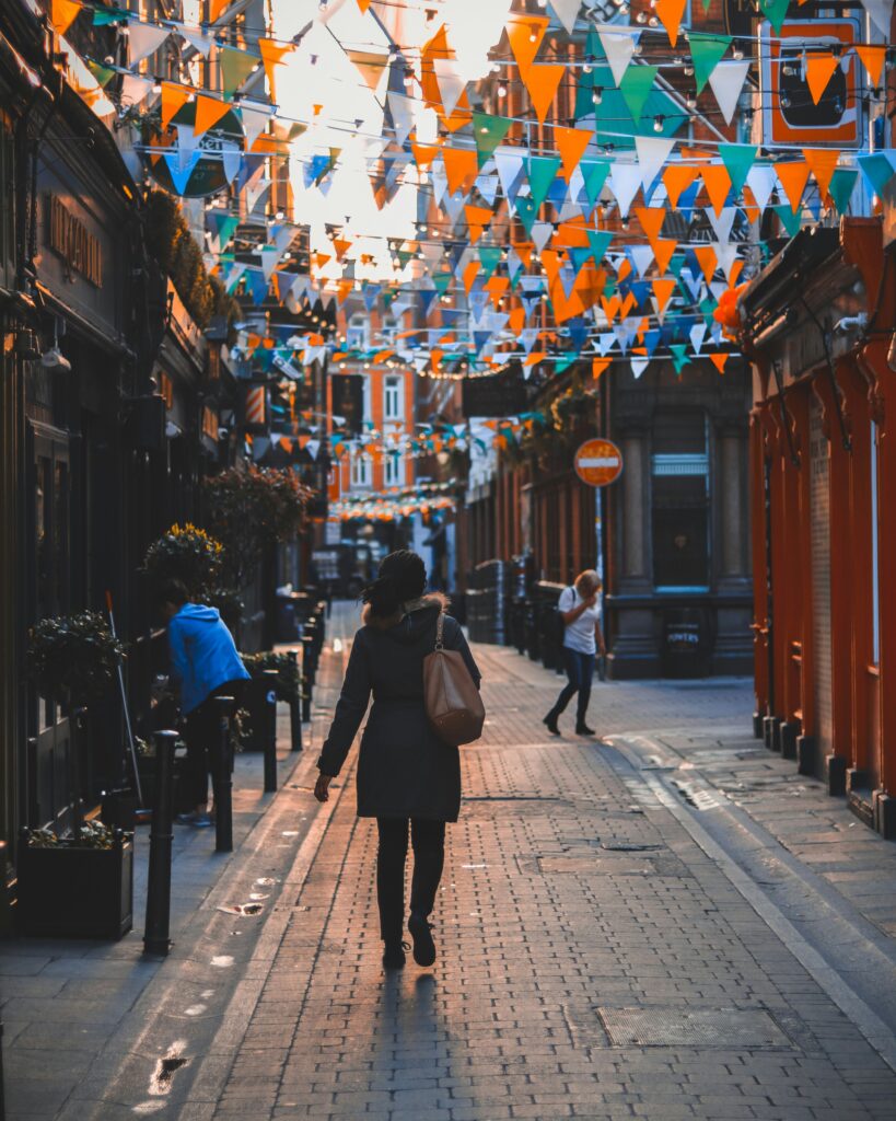 Woman walking through Dublin with St. Patrick's Day bunting on buildings