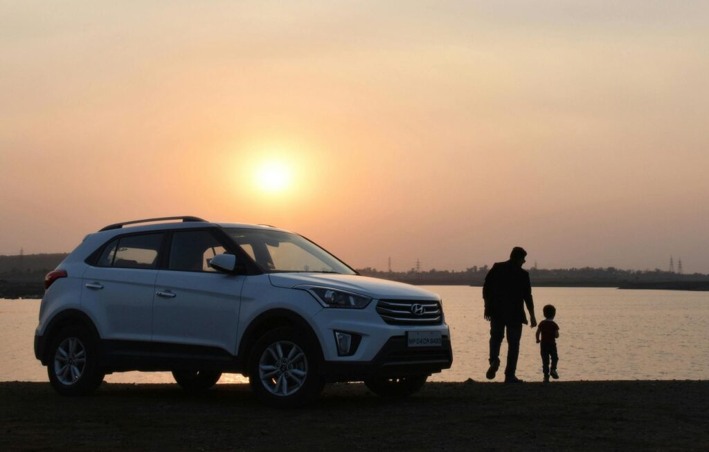 Father and child holding hands by a car
