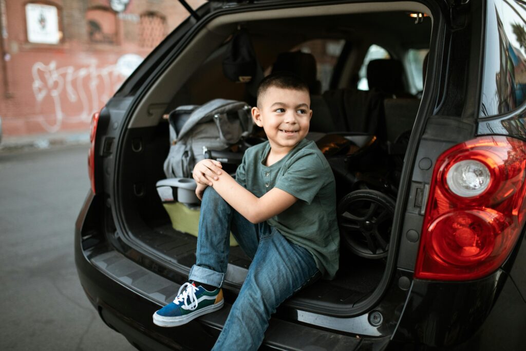 Boy sitting on the boot of a car