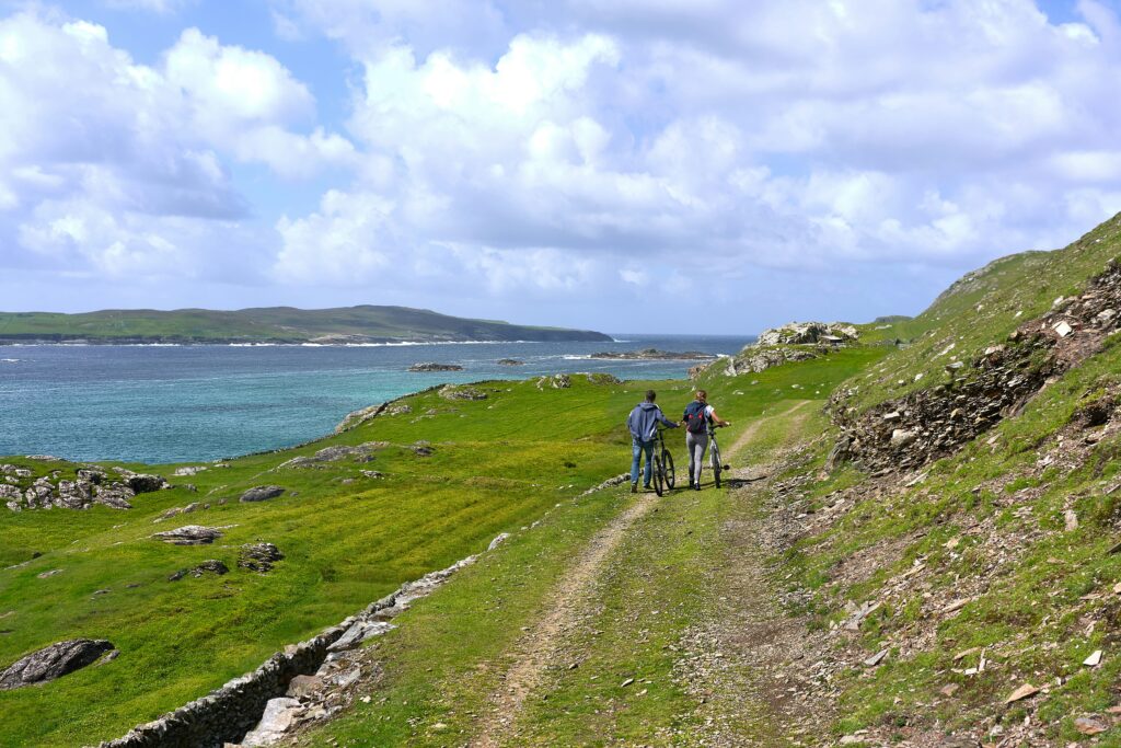 Two people pushing bikes on Inishbofin Island, County Galway