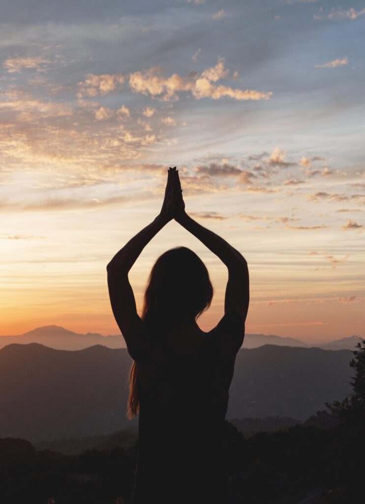 Silhouette of a woman practising yoga at sunrise
