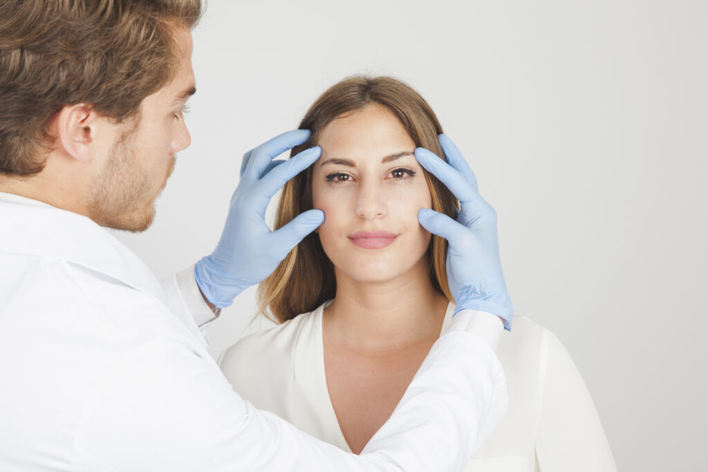 Doctor with blue gloves holding a patient's face