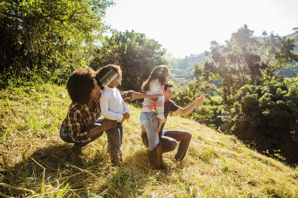 Happy family looking at nature on a hill in the sunshine