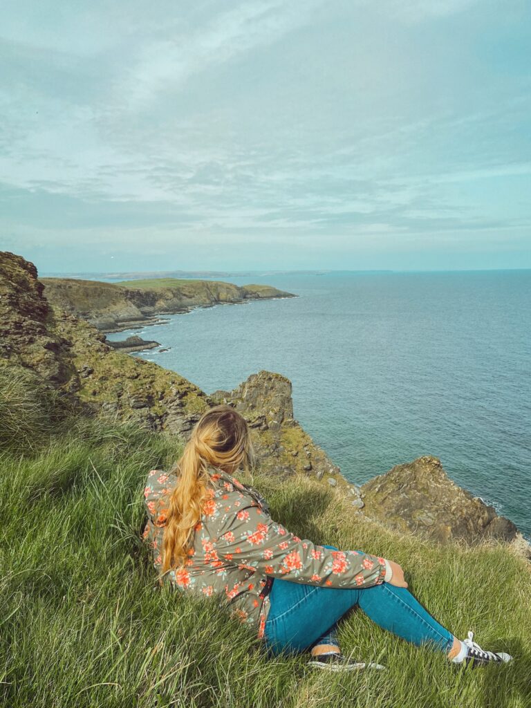 Woman sitting on the cliffs in Ireland