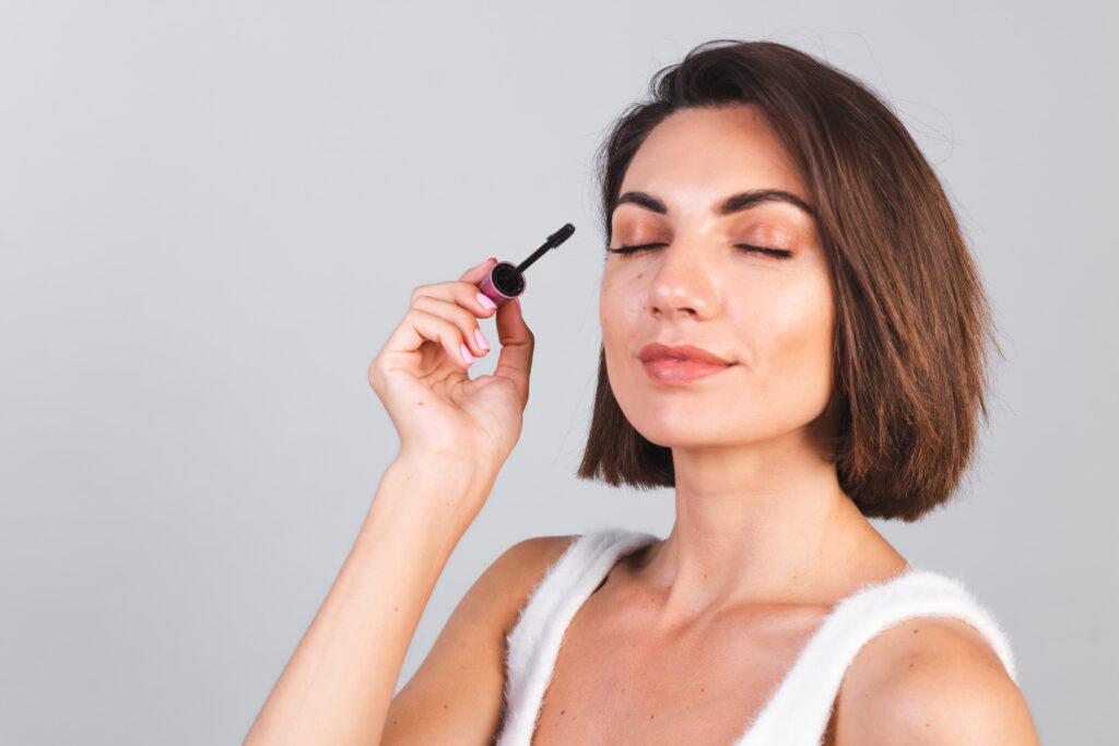 Woman with brown hair applying makeup