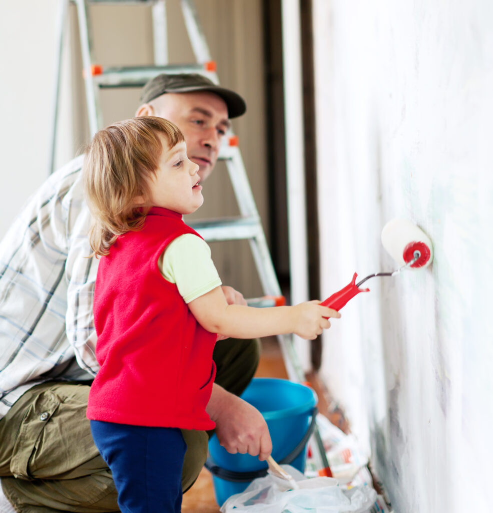 Child painting a wall with father