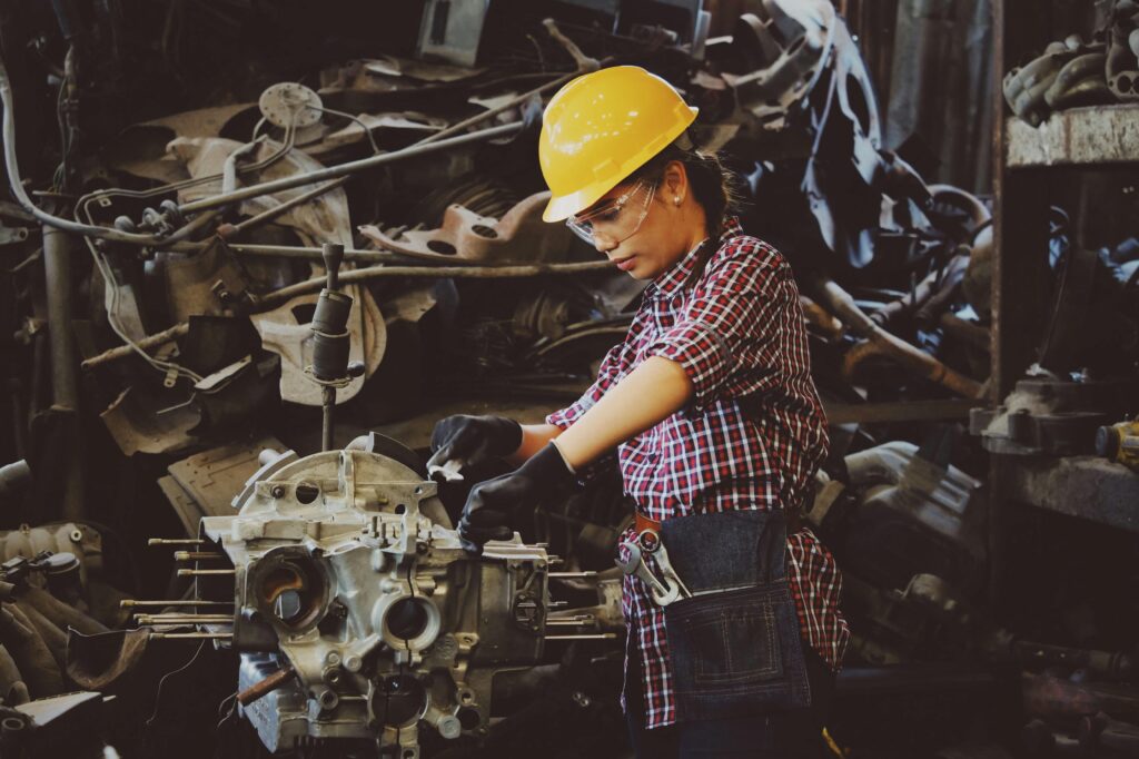 Woman with yellow hard hat working on a machine