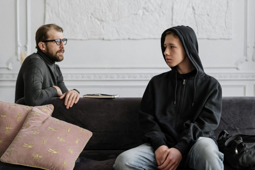 Man sitting with a teen boy in a black hoodie