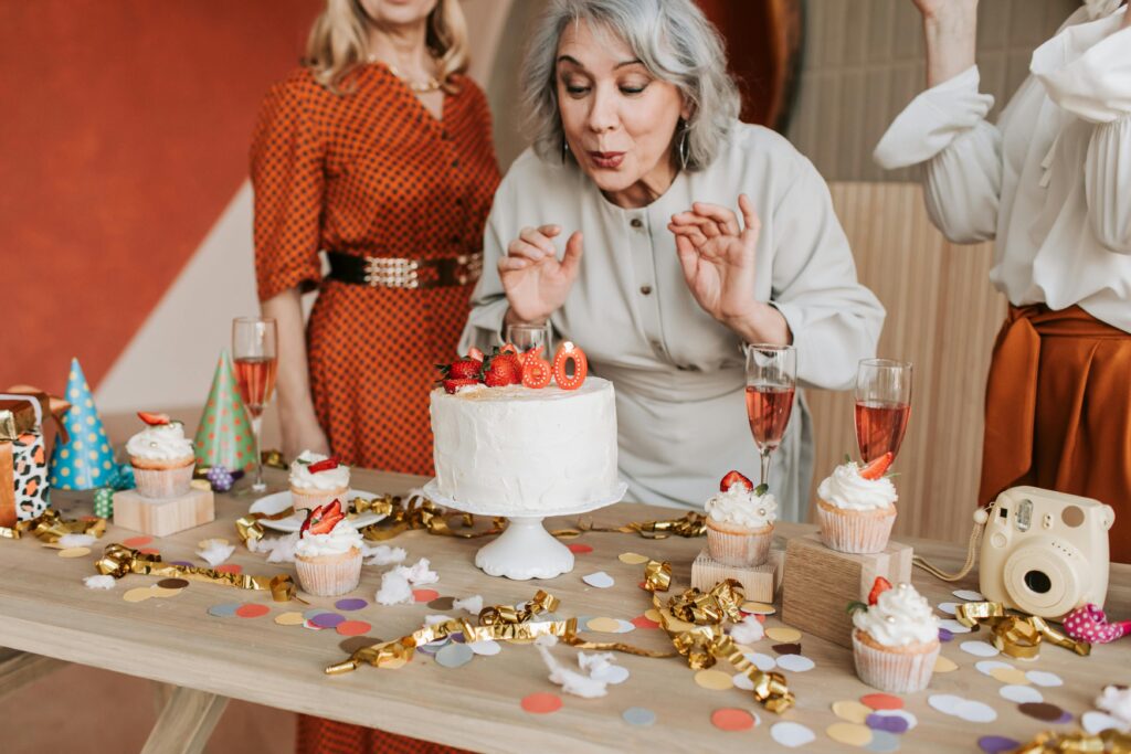 Adult woman blowing out candles on a birthday cake at a party