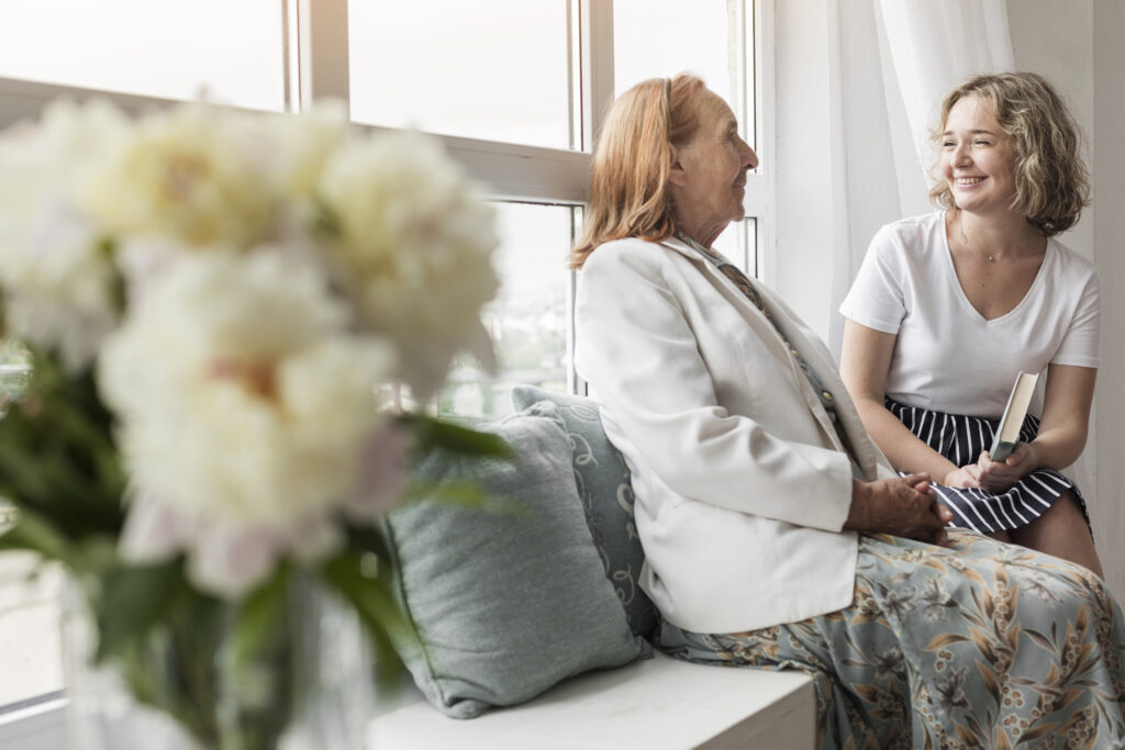Elderly woman sitting on a window seat with a younger woman