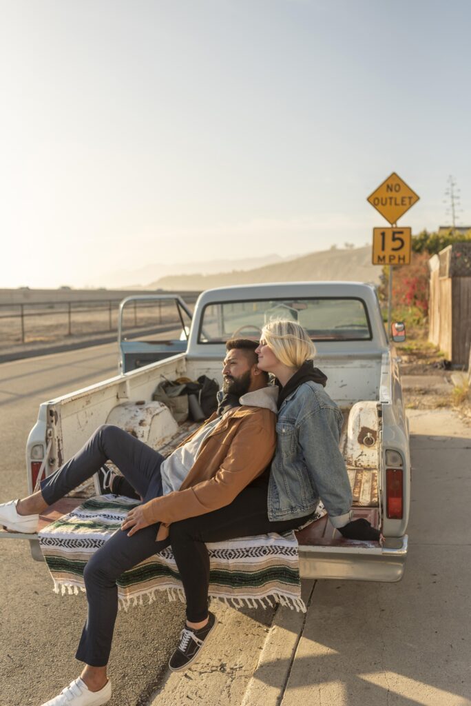 Young couple cuddling in the back of a pick up truck