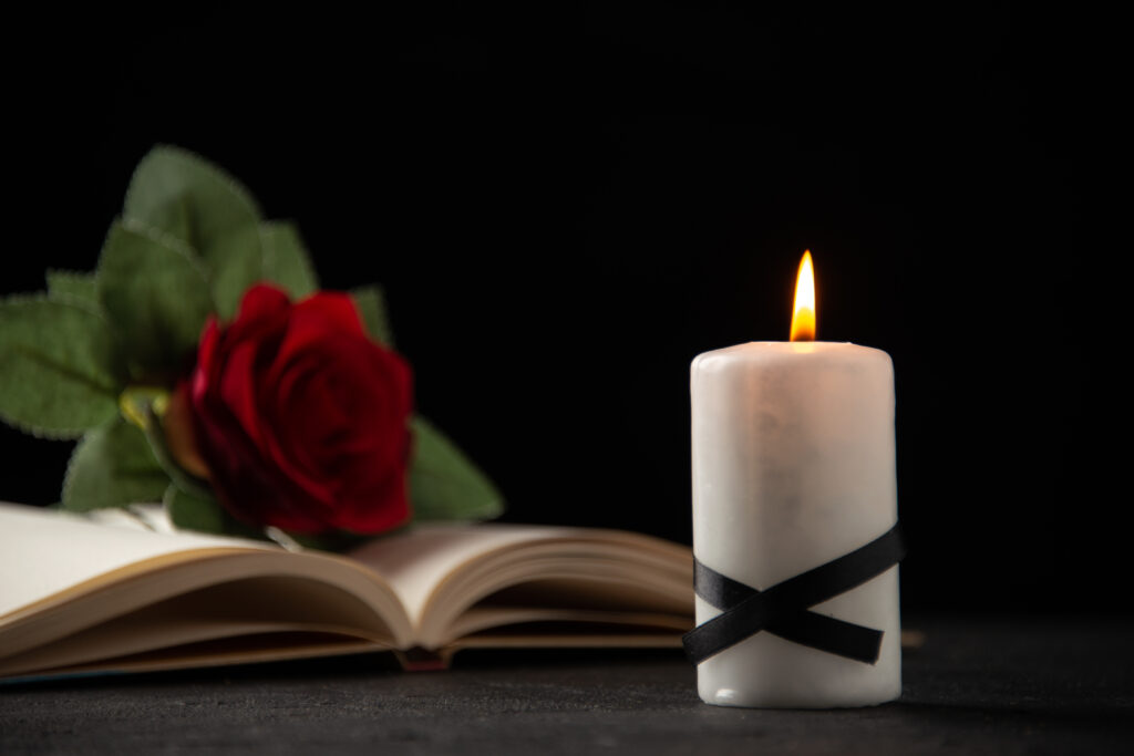 Red rose on a book with a black ribbon candle