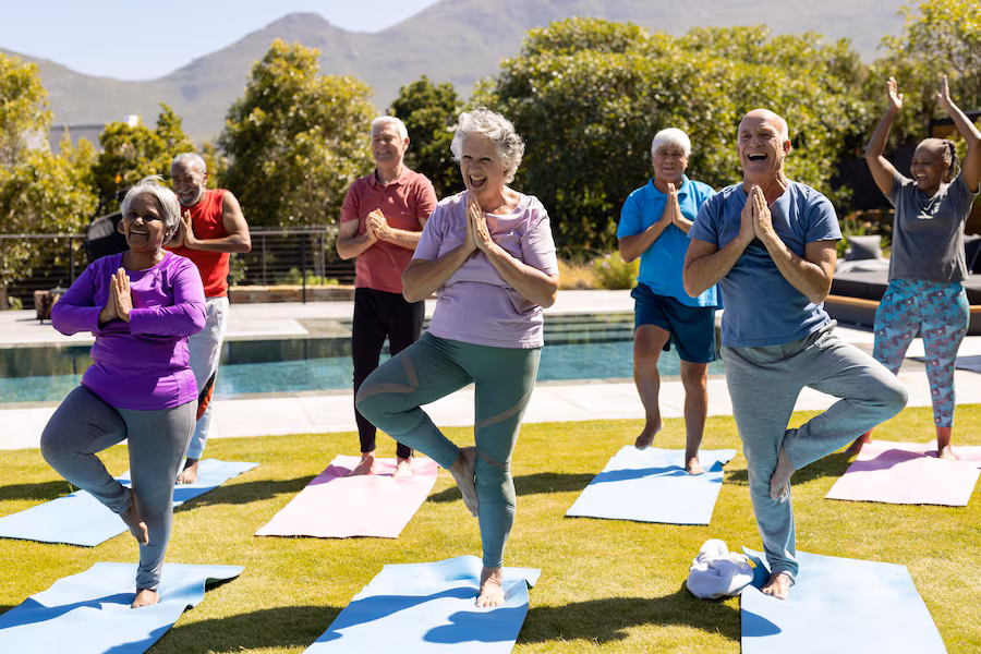 Senior friends practicing yoga in a sunny garden