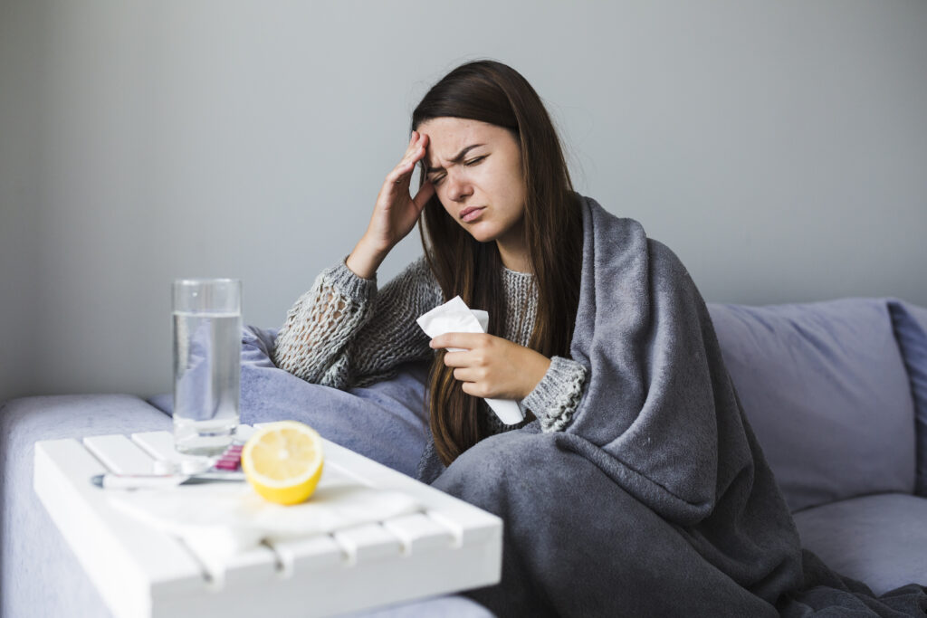 Woman sitting on a couch with medication while ill