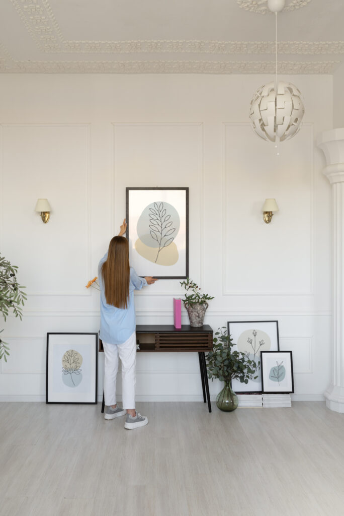 Woman hanging art prints on a wall