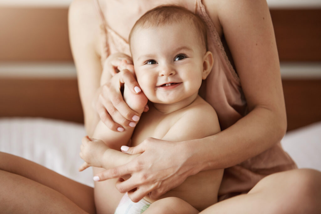 Mother and baby sitting on a bed