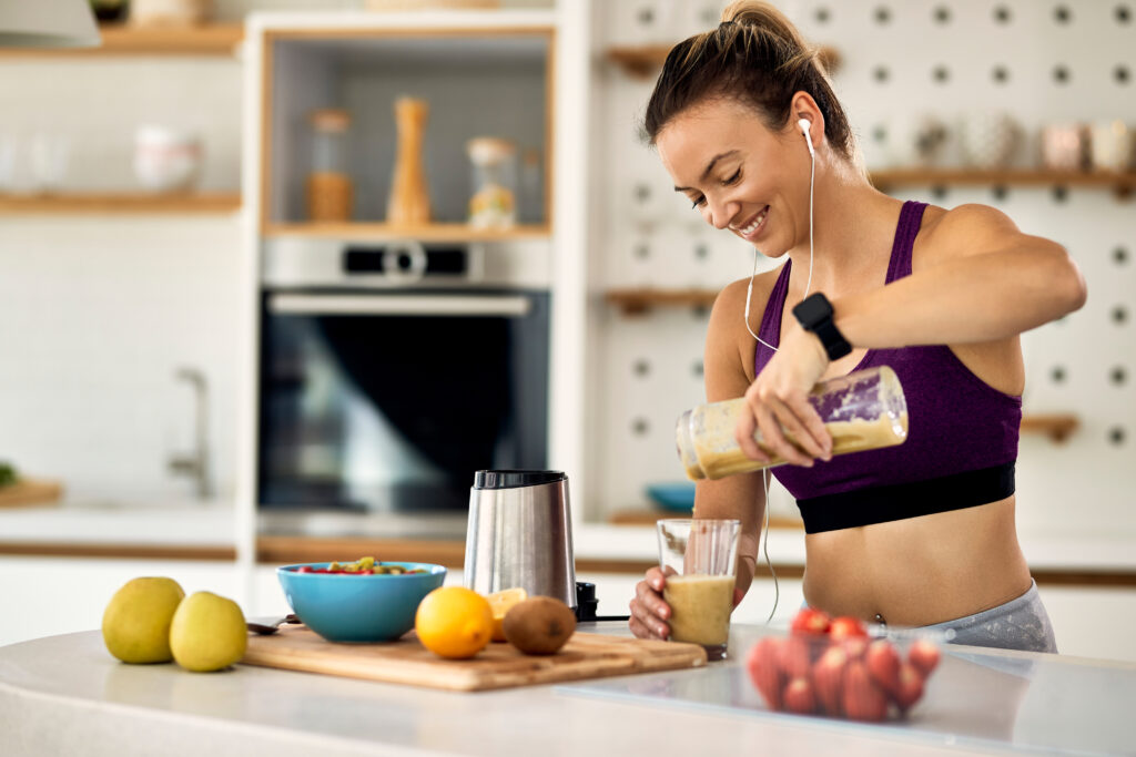 Young happy athletic woman making a protein smoothie