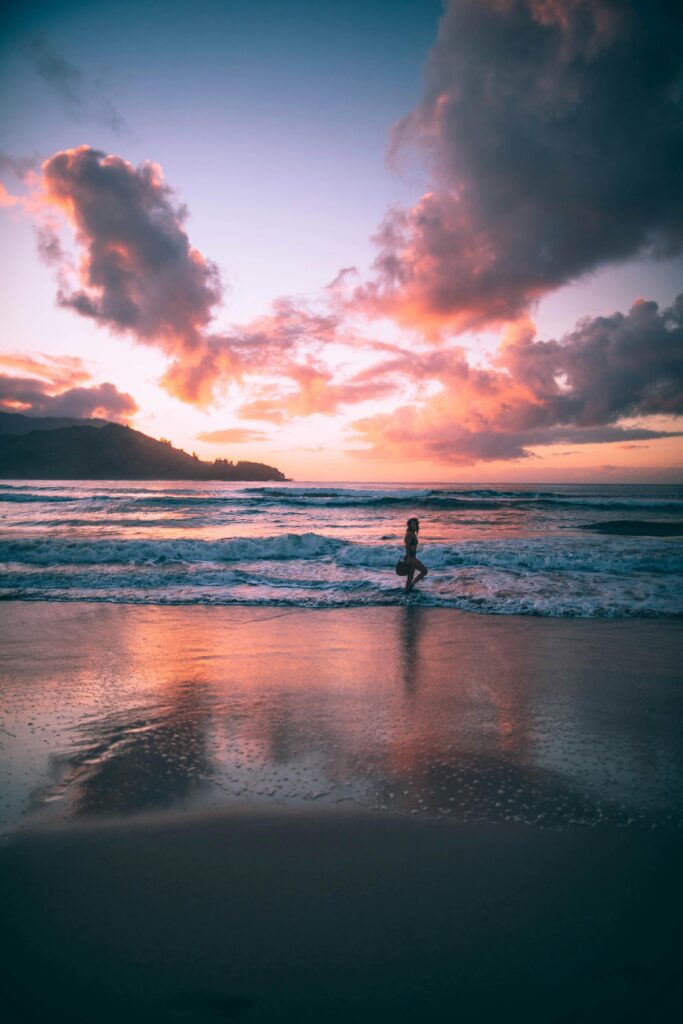 Woman walking on the seashore at sunset in Hanalei