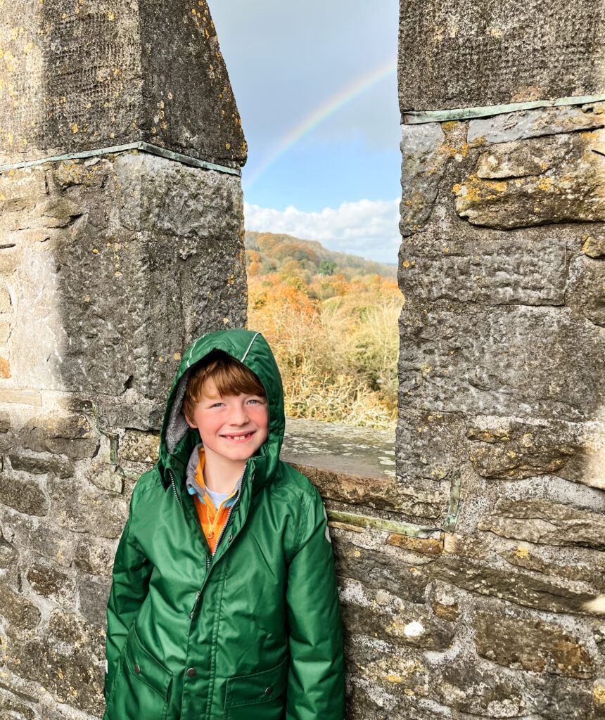 Child standing at the top of Bunratty Castle with a rainbow in the background