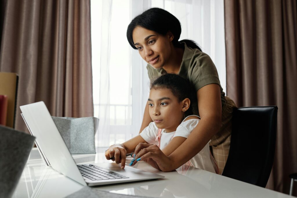 Mother helping child learn at a laptop
