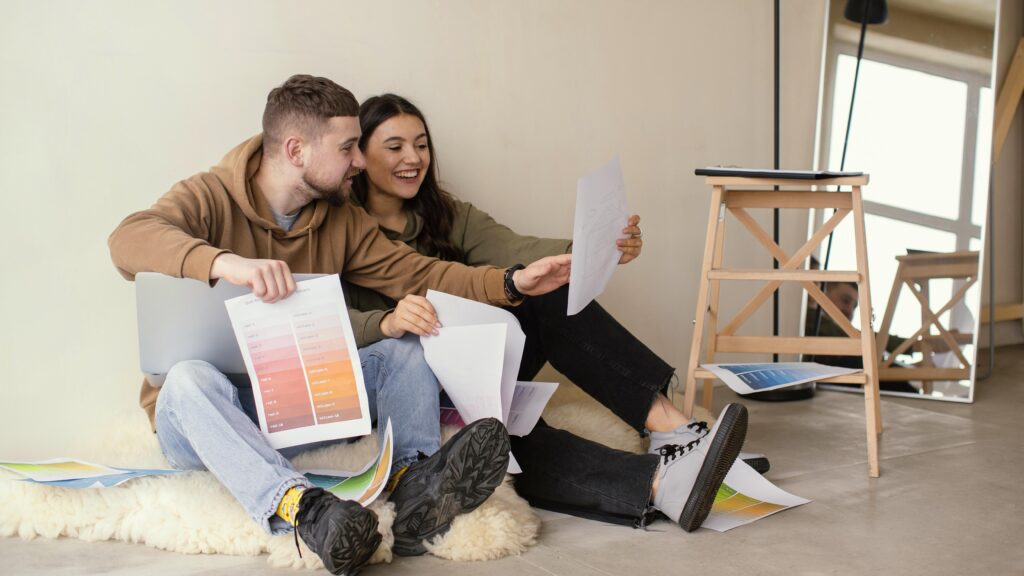 Smiley couple sitting on floor looking at papers