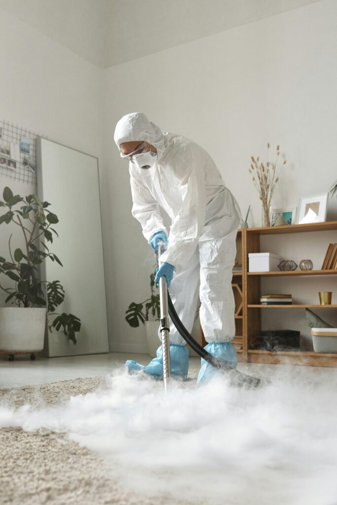 Person in white suit cleaning a carpet