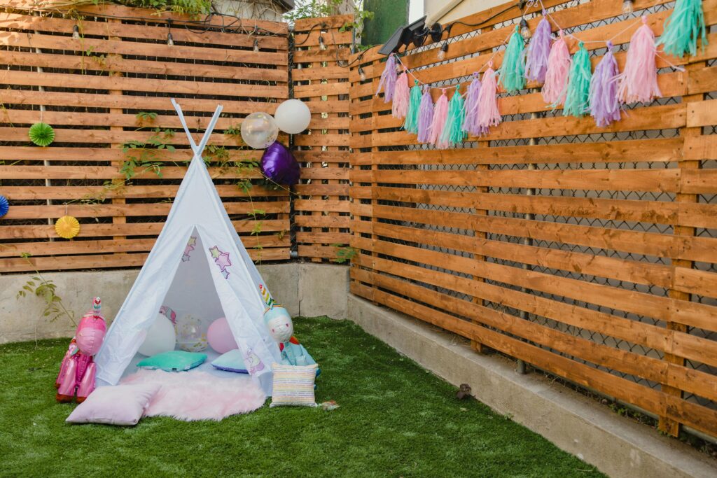 Tent in a garden with balloons and a banner on a fence
