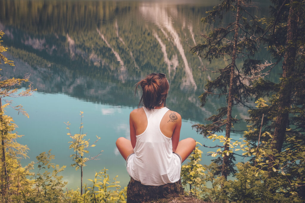 Woman in a white tank top sitting looking at a beautiful view